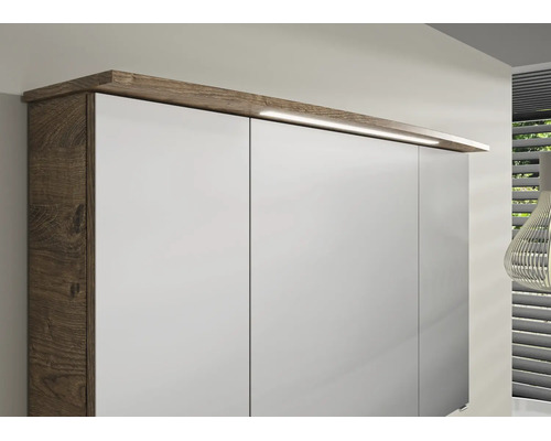 Kleiderschrank mit weissen Fronten, Korpus in dunkler Holzoptik und integrierter LED-Beleuchtung am Oberboden.