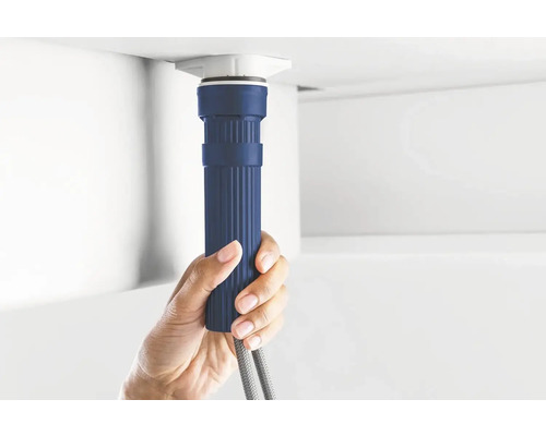 Eine Person hält einen blauen Siphon unter einem Waschbecken