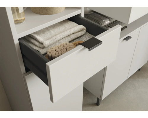 Meuble de salle de bains avec tiroir ouvert, rempli de serviettes et brosse.