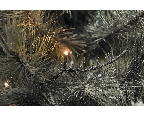 Gros plan d''un sapin artificiel illuminé avec de la neige