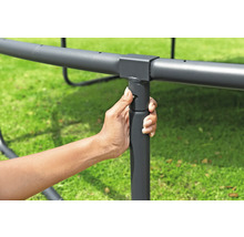 Une main fixe un pied de trampoline au cadre.