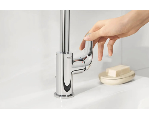 Robinet de lavabo brillant avec mitigeur monocommande et logo Grohe actionné par une main.