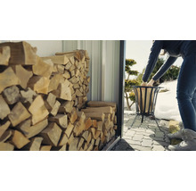 Une femme remplit un panier à bois avec du bois provenant d''un abri à bois.