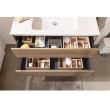 Meuble-lavabo de salle de bains avec tiroirs ouverts et divers articles de toilette pour le rangement
