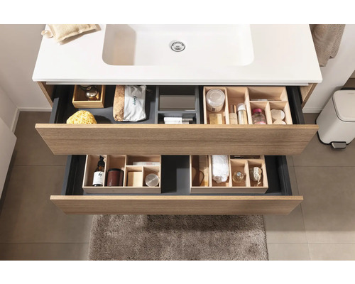 Meuble-lavabo de salle de bains avec tiroirs ouverts et divers articles de toilette pour le rangement