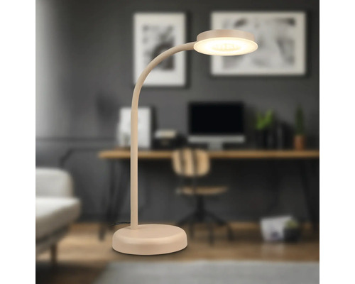 Beige Tischleuchte mit rundem Lampenkopf vor einem Arbeitsplatz