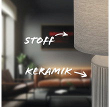 Detailaufnahme einer Lampe mit Stoffschirm und Keramikfuß in einem Wohnzimmer.