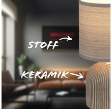 Nahaufnahme einer Tischleuchte mit Lampenschirm aus Stoff und Keramikfuß in einem Wohnzimmer.