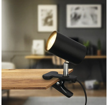 Schwarze Klemmleuchte an einem Holztisch