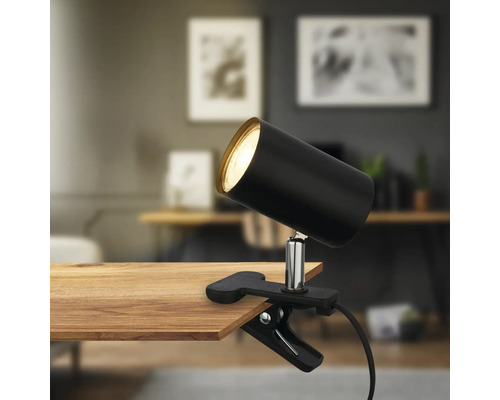Schwarze Klemmleuchte an einem Holztisch