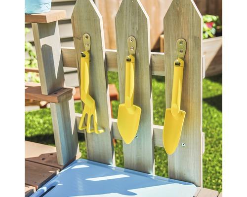 Ensemble de jardinage jaune pour enfants comprenant râteau et pelles, suspendu à une clôture en bois