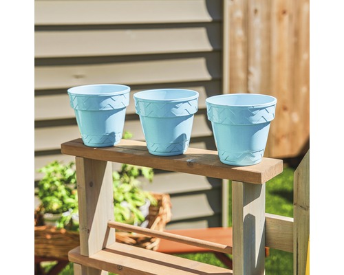 Trois pots de fleurs en plastique à motifs sur une étagère en bois