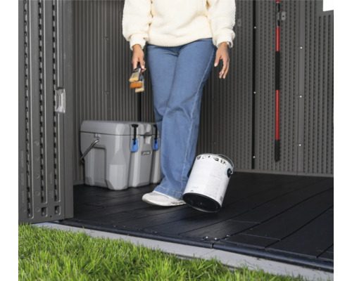 Vue intérieure d'une remise de jardin avec des dalles de sol, un pot de peinture et une glacière