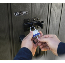 Une personne ferme un abri de jardin Lifetime avec un cadenas