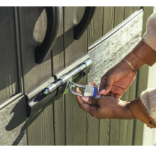 Une personne sécurise une porte avec un verrou à boulon et un cadenas.