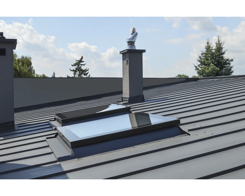 Vue de toit avec toit métallique, fenêtres de toit et cheminées