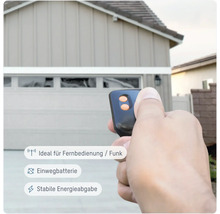 Garagentoröffner-Fernbedienung in der Hand vor Garage