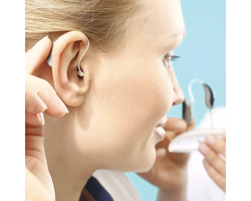 Frau setzt ein Hinter-dem-Ohr Hörgerät ein
