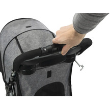 Detailaufnahme eines grauen Kinderwagens mit Hand, die den Griff berührt