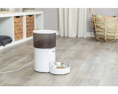 Automatischer Futterautomat für Haustiere mit Futternapf in einem hellen Raum.