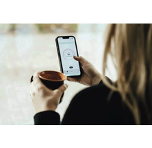 Femme avec tasse et smartphone pour le contrôle de la température