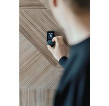 Personne ajustant un thermostat Smart Home sur un mur en bois