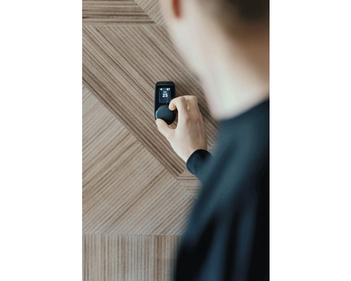 Personne ajustant un thermostat Smart Home sur un mur en bois