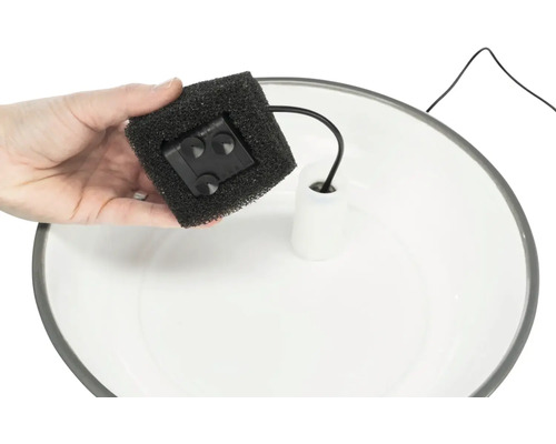 Hand hält einen Springbrunnenfilter über eine Springbrunnenschale