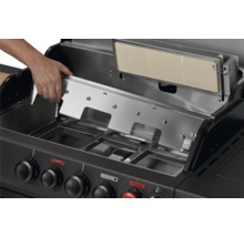 Gros plan d'un barbecue à gaz avec une main plaçant un couvercle.