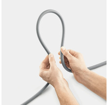 Un tuyau gris est tenu par deux mains.