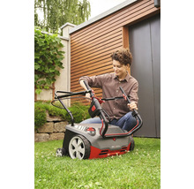 Eine Frau bedient einen Vertikutierer im Garten.