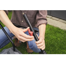 Eine Person montiert den Griff eines Rasenmähers mit einem roten Knopf.