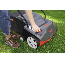 Eine Person bedient einen Vertikutierer auf einer Rasenfläche.