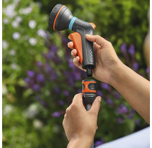 Une douche de jardin est raccordée à un tuyau d'arrosage. Le produit est en plastique.