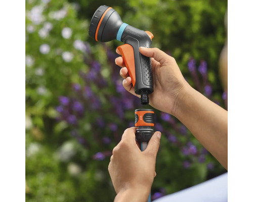 Une douche de jardin est raccordée à un tuyau d'arrosage. Le produit est en plastique.