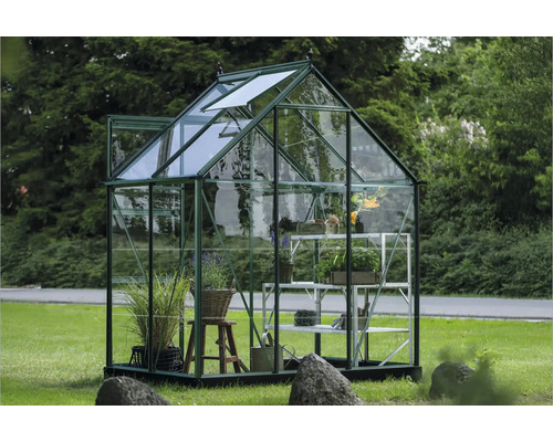 Gewächshaus mit Pflanzen und Regal auf einer Wiese