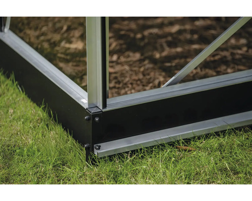 Detailansicht eines Gewächshausfundaments aus Aluminium und Kunststoff auf Rasen.