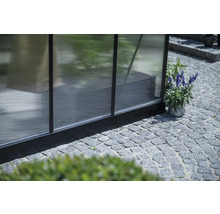 Detailansicht eines Gewächshauses mit Pflastersteinen im Außenbereich.