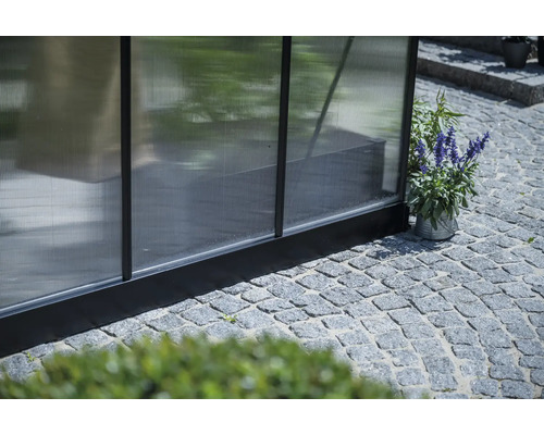 Detailansicht eines Gewächshauses mit Pflastersteinen im Außenbereich.