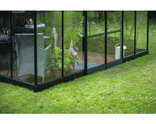 Gewächshaus mit Pflanzkübel, Stuhl und Giesskanne im Garten