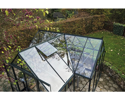 Ein Gewächshaus mit geöffnetem Fenster in einem Garten.