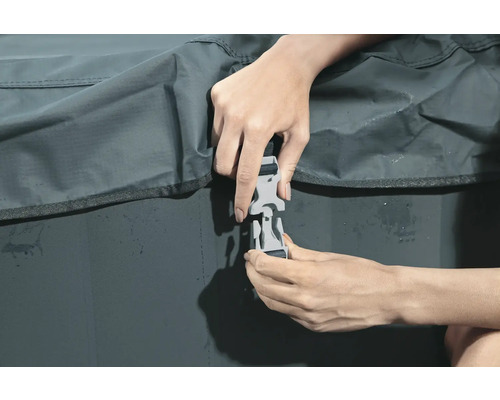 Eine Person befestigt die Schnalle einer Abdeckung.