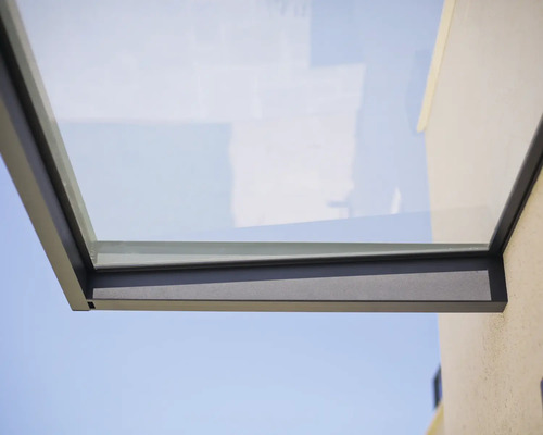 Marquise moderne en verre avec cadre métallique anthracite sur un mur extérieur.
