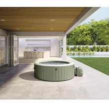 Jacuzzi gonflable sur une terrasse avec jardin en arrière-plan.