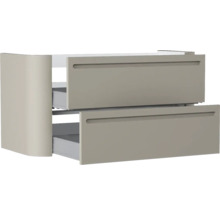 Waschtischunterschrank mit zwei leicht geöffneten Auszügen, integrierten Griffmulden und abgerundeter Seitenwand in Taupe.