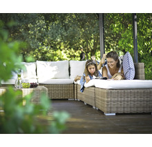 Une mère et sa fille se détendent sur un canapé en rotin dans le jardin sous un pavillon.