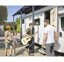 Familie mit Gitarre unter einem Terrassendach neben einem Wohnmobil