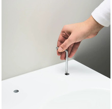 Eine Person führt einen Inbusschlüssel in ein Loch in einer weißen Oberfläche ein