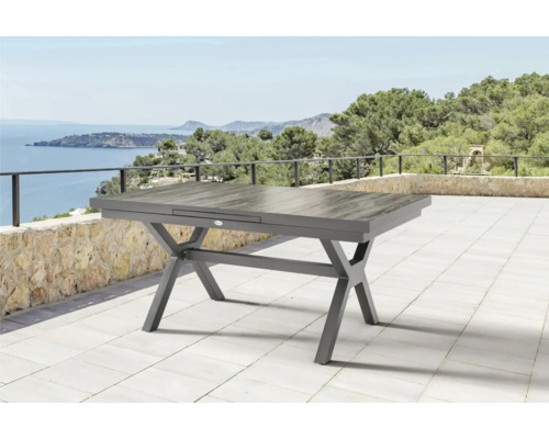 Table de jardin extensible avec cadre en aluminium sur une terrasse avec vue sur la mer