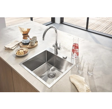 Évier de cuisine en acier inoxydable avec robinet sur un comptoir de cuisine avec nourriture et boissons